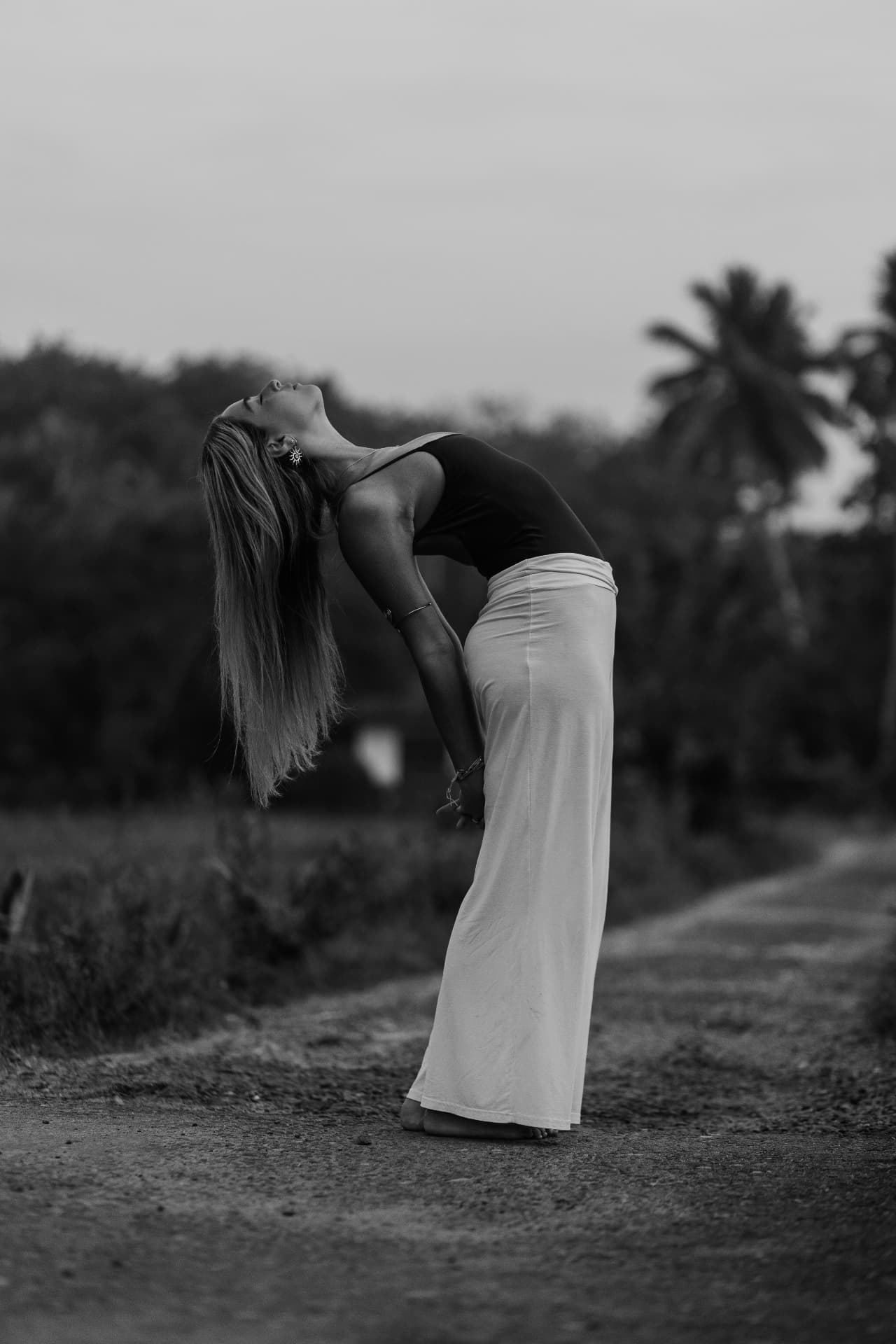 Lia Sofer in a standing backbend on a quiet road at dusk